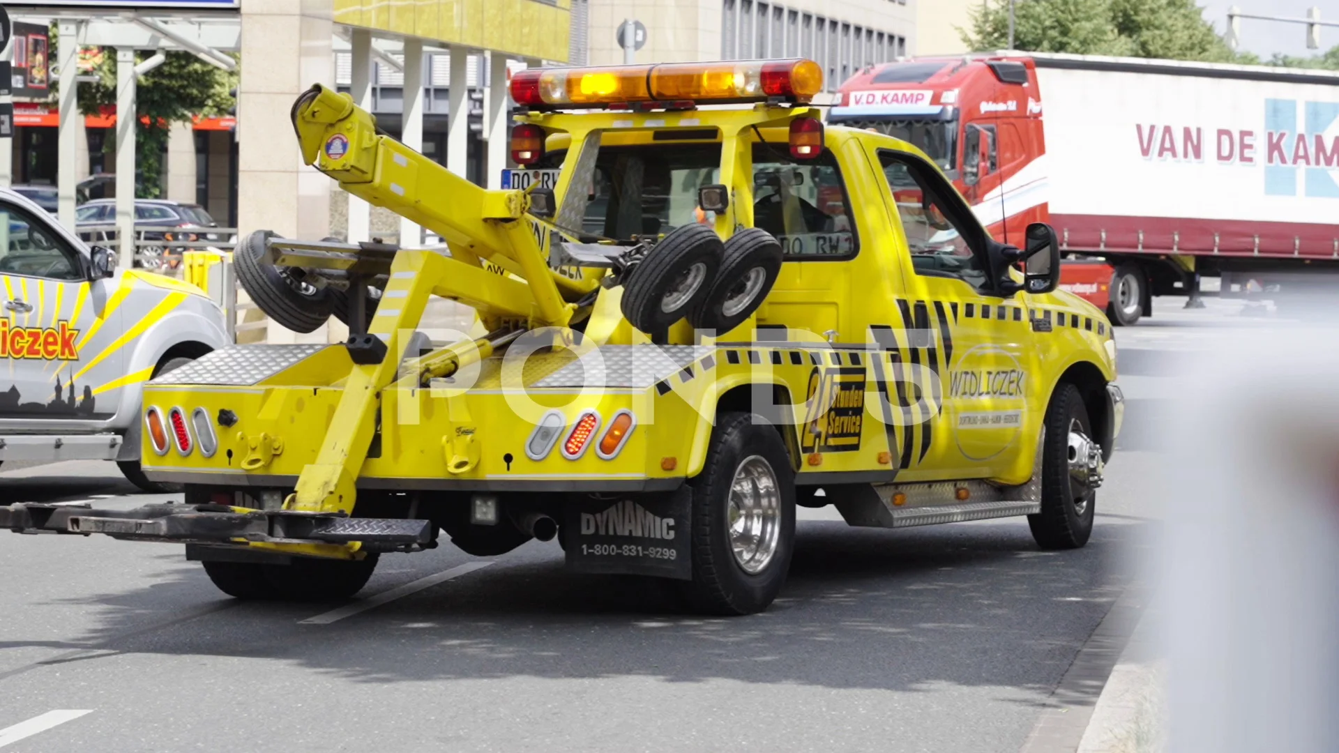 Tow service truck backing up with flashing lights