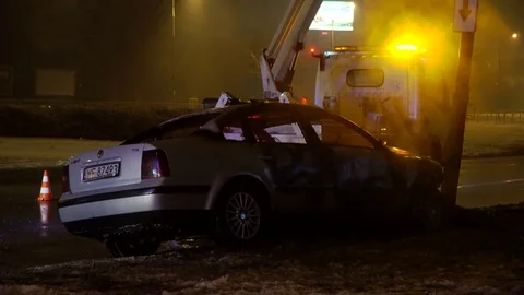 A tow truck driver prepares a crashed car to be towed on a winter night in Stock Footage 102133972