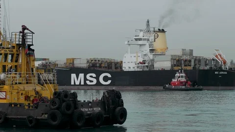 A towboat is escorted by a huge container ship in the port Stock Footage 88838053