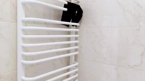 Towel Warmer with Black Socks Drying in Bright Tiled Bathroom Vidéo 312866689