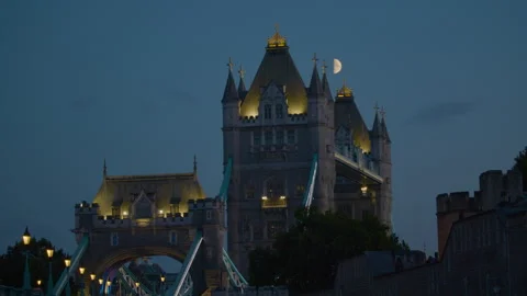 Tower Bridge at dusk with lights glowing and a half-moon overhead. Stock Footage 321607674