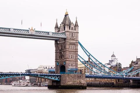 Tower Bridge spanning River Thames with a riverboat passing by on a cloudy .. Fotos de archivo