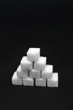 Tower built out of sugar white cubes on isolated black background Stock Photos