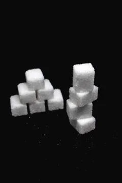 Tower built out of sugar white cubes on isolated black background Stock Photos