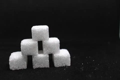 Tower built out of sugar white cubes on isolated black background Stock Photos