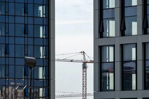 Tower construction crane between modern high-rise buildings with concrete and Stock Photos