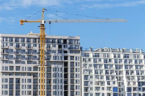 Tower construction crane in front of finished  apartment building. Stock Photos