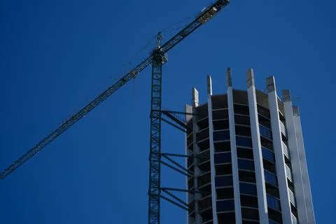 Tower crane in action construction of a new round shaped multi-storey building Stock Photos