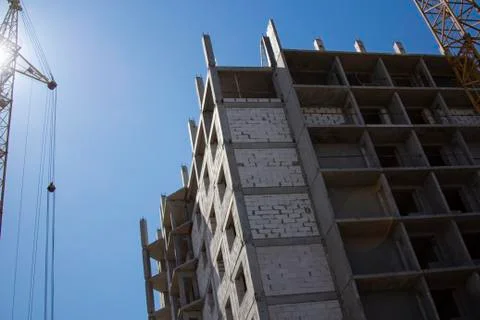Tower crane and construction of a multi-story building against the blue sky.  Stock Photos