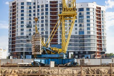 A tower crane assembles gutter panels during the construction Stock Photos