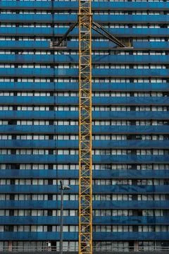 Tower crane attached to the wall of a blue building, construction site Stock Photos