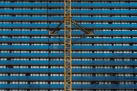 A tower crane attached to the wall of a blue building, construction site Stock Photos