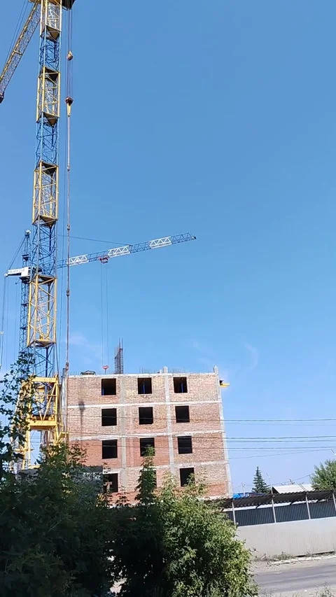 Tower crane beside rising brick building under clear blue sky construction site Vídeos de archivo 346985589