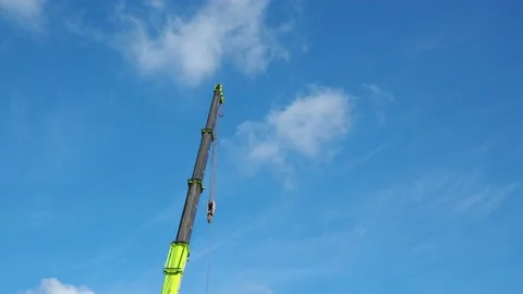 Tower Crane Boom Fully Extended with Hoist Chain Swaying Against Blue Sky Stock Footage 138187534