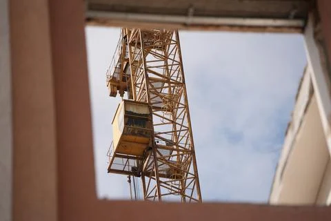 Tower crane cabin through the window of a house under construction Stock Photos