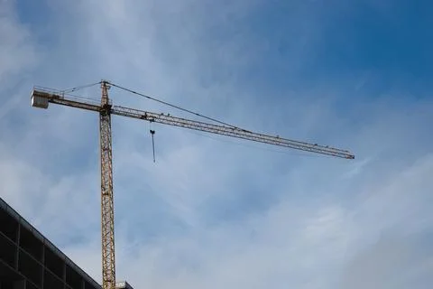 A tower crane at a construction site with a raised boom with blue sky in th.. Stock Photos