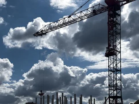 Tower crane on a construction site under dramatic clouds. Industrial lifting Stock Photos