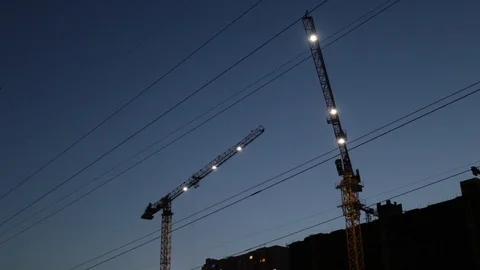 Tower crane with lanterns works after sunset movement of a boom at a constructio Stock Footage 120142793