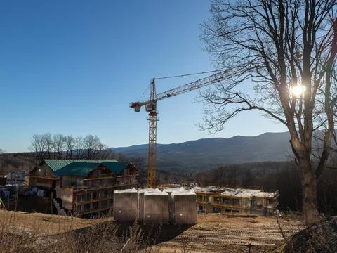 A tower crane looms over an active mountain resort construction site with Stock Photos