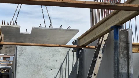 Tower crane lowering prefabricated concrete floor slab into place Stock Footage 336743324