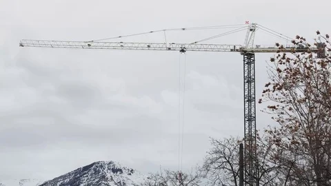 Tower crane mountain in background blowing tree foreground Stock Footage 72888418