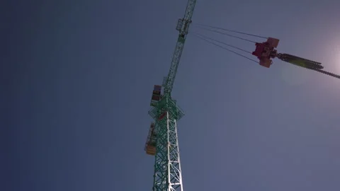 Tower crane operating against clear blue sky at construction site 動画素材 347160698