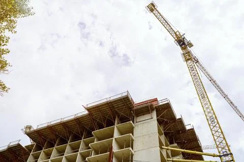 Tower crane operating at a multi-level concrete building frame construction 库存照片