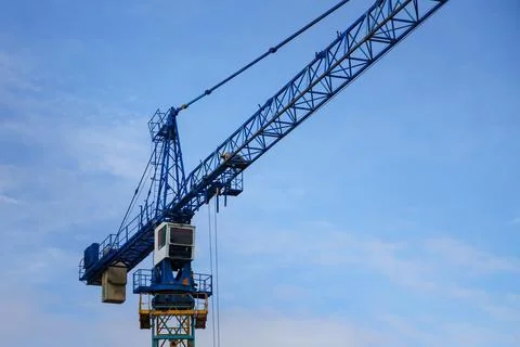 Tower crane operator's cab with part of the boom on a background of blue sky. Stock Photos