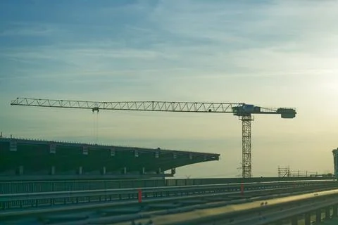 Tower crane over bridge structure during early morning construction work Stock Photos