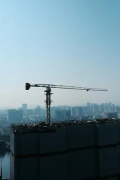 Tower crane over high-rise building in city skyline Stock Photos