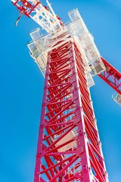 Tower crane, red against the sky and mountains Stock Photos