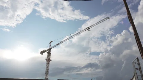Tower crane rises against sky forming industrial silhouette Stock Footage 327795619
