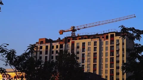A tower crane rotates its boom. A construction site with a multi-story resi.. Stock Footage 338319488