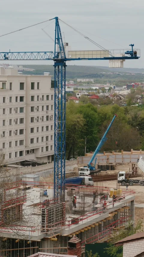 Tower crane rotating over a bustling urban construction site timelapse Stock Footage 345519383