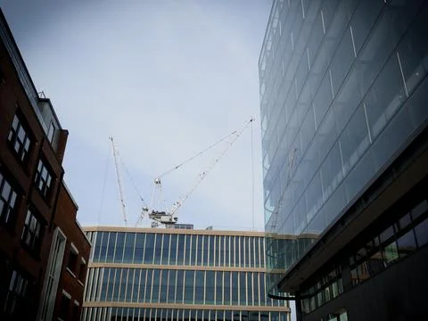 A tower crane seen framed by mixed modern glass and brick office buildings Stock Photos