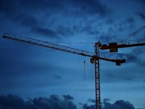Tower crane silhouette against dramatic evening sky Stock Photos