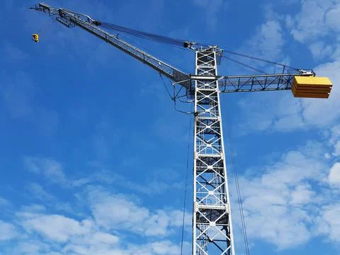 Tower crane for transporting heavy loads against the sky Stock Photos