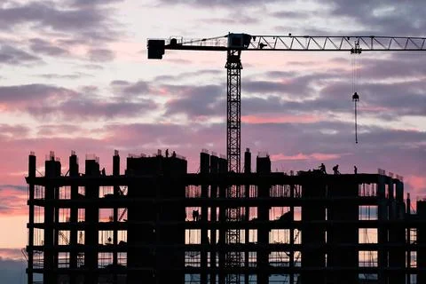 Tower crane, workers work at construction site. Process of building new houses Stock Photos