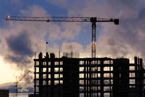 Tower crane, workers work at construction site. Process of building new houses Stock Photos