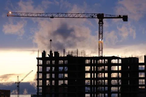 Tower crane, workers work at construction site. Process of building new houses Stock Photos