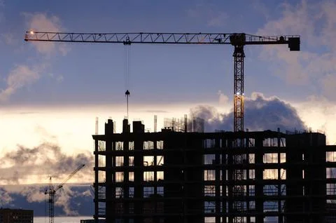 Tower crane, workers work at construction site. Process of building new houses Stock Photos