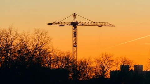 Tower crane working on construction evening sky trees trembling, golden hour Stock Footage 103992303