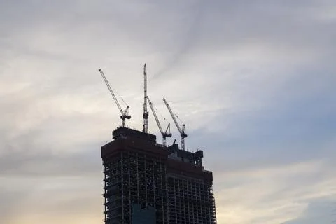 Tower cranes in action at construction site on sunset background. Crane the b 스톡 사진