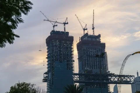Tower cranes in action at construction site on sunset background. Crane the b 스톡 사진