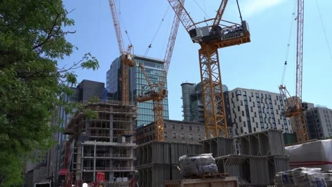 Tower cranes and construction materials stand before a rising concrete Stock Footage 335353419