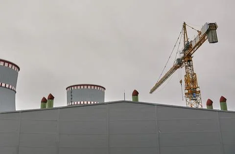 Tower cranes on the background of the cooling tower. Stock Photos