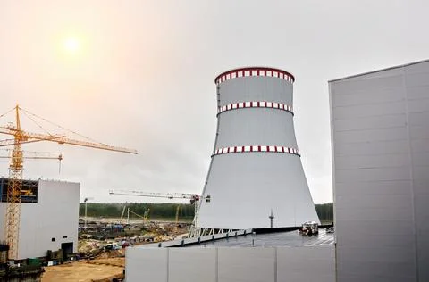 Tower cranes on the background of the cooling tower. Stock Photos