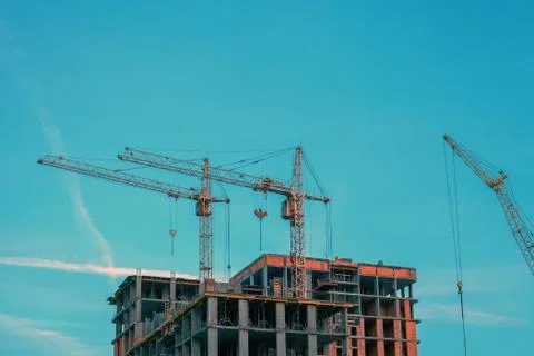 Tower cranes by blue cloudy sky Stock Photos