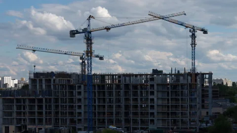 Tower cranes building apartment complex under clear summer sky timelapse vide Video stock 310664007