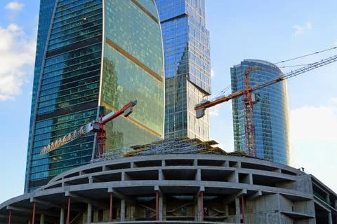 Tower cranes on the construction of a building on the background of skyscrapers Stock Photos